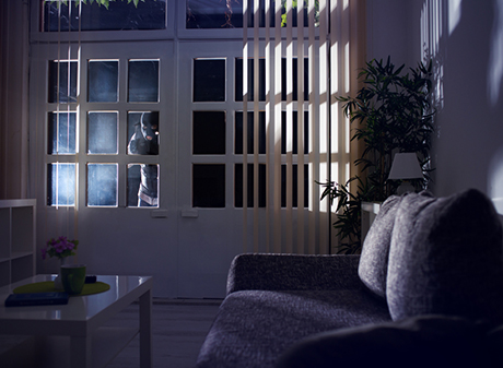 Burglar breaking into house through a window, highlighting the importance of security window film